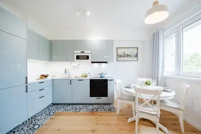 a kitchen with blue cabinets and a table and a table and chairs at Prague Days - One Bedroom Apartment with AC and Workspace in Holešovice in Prague