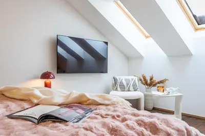 a bedroom with a bed with a book and a tv on the wall at Prague Days - Luxurious 3BDR Maisonette w AC & Balcony & Desk in Prague