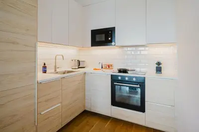 a kitchen with white cabinets and a black oven at Prague Days - Family Friendly One-Bedroom Apartment with Balcony, TV & Netflix in Holešovice in Prague