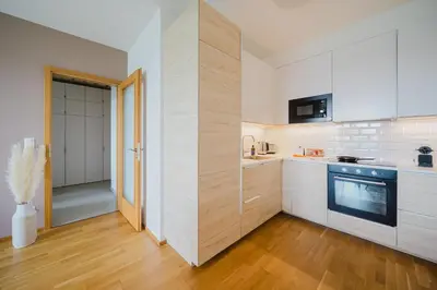 a kitchen with white walls and wooden floors at Prague Days - Family Friendly One-Bedroom Apartment with Balcony, TV & Netflix in Holešovice in Prague