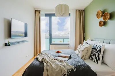 a bedroom with a bed with a view of the ocean at Prague Days - Family Friendly One-Bedroom Apartment with Balcony, TV & Netflix in Holešovice in Prague