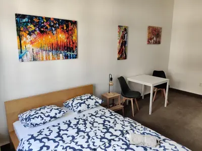 a bedroom with a bed and a table and a painting at Comfortable 2 Bedroom Flat Free Parking Shared Kitchen in Prague