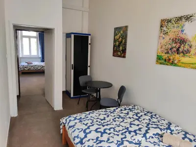 a bedroom with a bed and a table and a painting at Comfortable 2 Bedroom Flat Free Parking Shared Kitchen in Prague