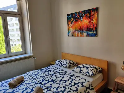 a bedroom with a bed and a painting on the wall at Comfortable 2 Bedroom Flat Free Parking Shared Kitchen in Prague