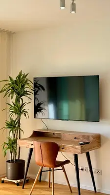 a desk with a television on a wall with a chair at Urban studio with balcony in Prague