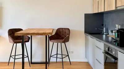 a kitchen with two bar stools and a table at Urban studio with balcony in Prague