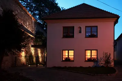 a white house with lights in the windows at Penzion Dobré Časy in Poděbrady