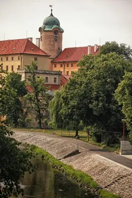 a building with a clock tower next to a river at Penzion Dobré Časy in Poděbrady