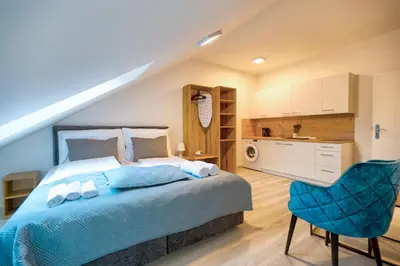 a bedroom with a blue bed and a kitchen at Prague Urban Apartments 48 in Prague
