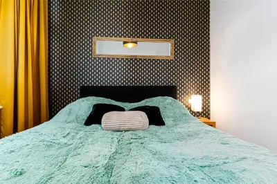 a bed with a green comforter with a pillow on it at Premium Dog Suite in Prague