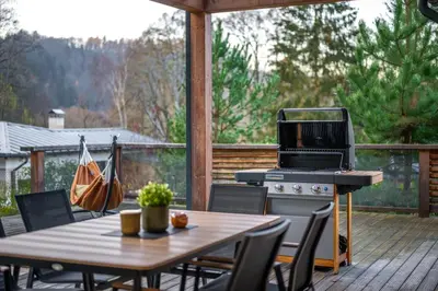 a patio with a table and a grill on a deck at Modern Nature Retreat w Pool, PS5 & Hot Tube in Sázava
