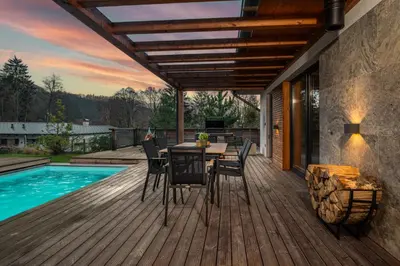 a deck with a table and chairs next to a swimming pool at Modern Nature Retreat w Pool, PS5 & Hot Tube in Sázava