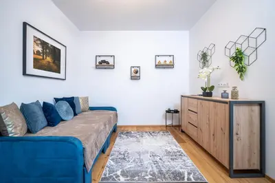 a living room with a blue couch and a dresser at Modern Nature Retreat w Pool, PS5 & Hot Tube in Sázava