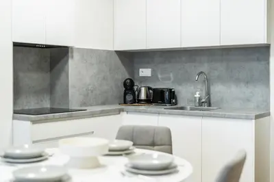 a kitchen with white cabinets and a table with dishes at Rentero Fresh Apartment next to Prague City Center in Prague