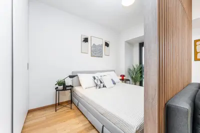 a white bedroom with a bed and a couch at Rentero Fresh Apartment next to Prague City Center in Prague