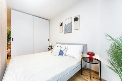 a white bedroom with a bed and a table at Rentero Fresh Apartment next to Prague City Center in Prague