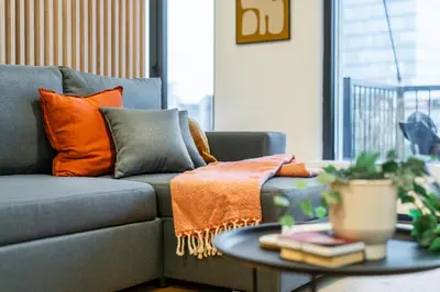 a gray couch with orange pillows and a table at Rentero Fresh Apartment next to Prague City Center in Prague