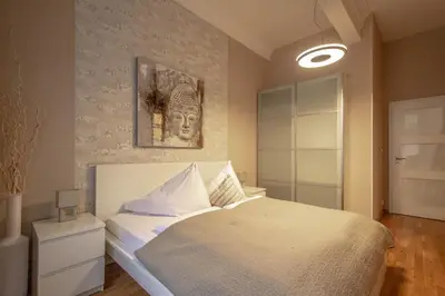 a bedroom with a white bed and a wall at Wenceslas Sq 3BDR Apartment in Prague