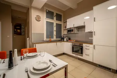 a kitchen with white cabinets and a table with plates on it at Wenceslas Sq 3BDR Apartment in Prague