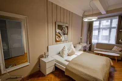 a bedroom with a white bed and a living room at Wenceslas Sq 3BDR Apartment in Prague