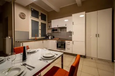 a kitchen with white cabinets and a table and chairs at Wenceslas Sq 3BDR Apartment in Prague