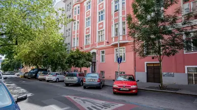 a row of cars parked in front of a pink building at Tower Apartment in Prague
