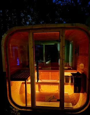 a glass door with a bench on a deck at night at Relax u potoka, vířivka, swimSpa, sauna
