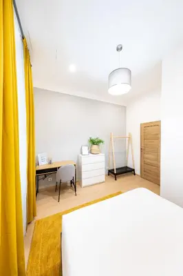 a bedroom with a desk and a yellow curtain at Bohéme Apartments Folimanka in Prague