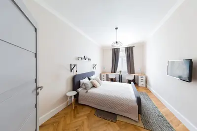 a white bedroom with a bed and a tv at Bohéme Apartments Folimanka in Prague