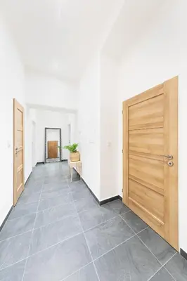 an empty hallway with a wooden door and a chair at Bohéme Apartments Folimanka in Prague
