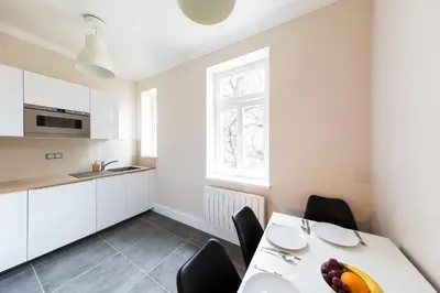 a white kitchen with a white table and chairs at Bohéme Apartments Folimanka in Prague