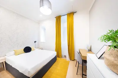 a bedroom with a white bed and a desk with a desk at Bohéme Apartments Folimanka in Prague