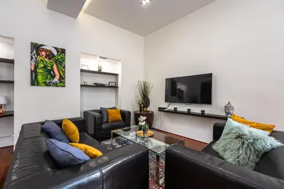 a living room with two leather couches and a tv at Spacious elegant apartment at the Old Town Square in Prague