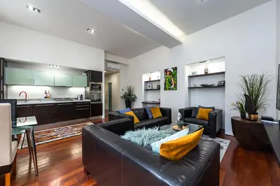 a living room with a leather couch and a kitchen at Spacious elegant apartment at the Old Town Square in Prague