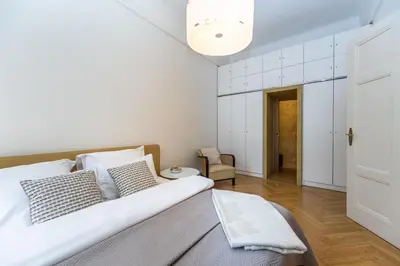 a white bedroom with a bed and a chair at Bohemian charm apartment by Paris Avenue 1 in Prague