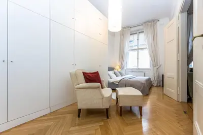 a white bedroom with a bed and a chair at Bohemian charm apartment by Paris Avenue 1 in Prague