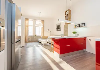 a kitchen with red cabinets and a living room at Cozy apartment with 2 bedrooms in New Town in Prague
