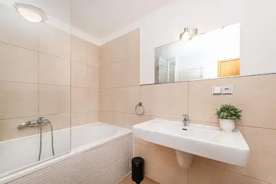 a bathroom with a sink and a tub and a mirror at Amazing 3-Bedroom and Terrace overlooking TV Tower in Prague