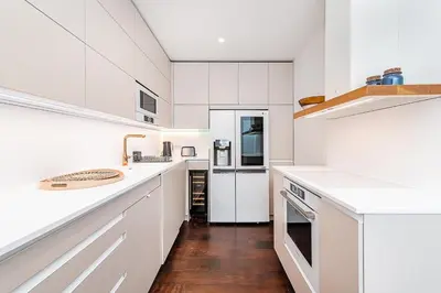 a white kitchen with white appliances and wooden floors at Amazing 3-Bedroom and Terrace overlooking TV Tower in Prague