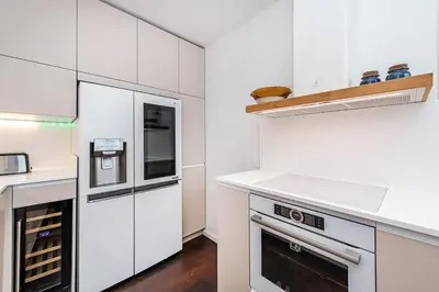 a white kitchen with white cabinets and appliances at Amazing 3-Bedroom and Terrace overlooking TV Tower in Prague
