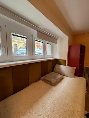 a small bed in a room with two windows at Negroni Apartment in Prague