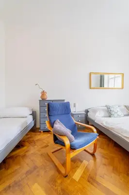 a blue chair in a room with two beds at Charming Apartment in the Heart of Prague by Rentez in Prague