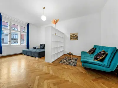 a living room with a blue couch and a bed at Spacious & Modern Apartment by Wenceslas Square in Prague