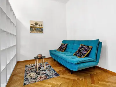 a living room with a blue couch and a table at Spacious & Modern Apartment by Wenceslas Square in Prague