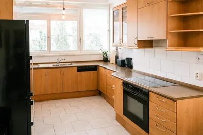 a kitchen with wooden cabinets and a black refrigerator at Bright 120m apartment 2BR Balconies near Castle in Prague