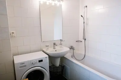 a bathroom with a sink and a washing machine at Bright 120m apartment 2BR Balconies near Castle in Prague
