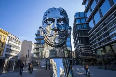 a statue in the middle of a city with buildings at Charming Attic Apartment in the Heart of Prague in Prague