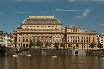 a large building on the river with boats in the water at Charming Attic Apartment in the Heart of Prague in Prague