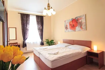 a bedroom with a bed and a window and flowers at Penzion U Čejpu in Prague