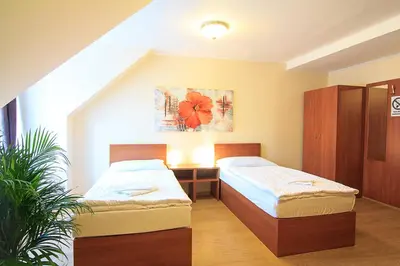 a bedroom with two beds and a potted plant at Penzion U Čejpu in Prague